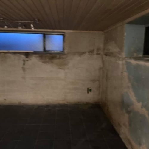 Kælder før renovering med rå vægge og flisegulv i Esbjerg